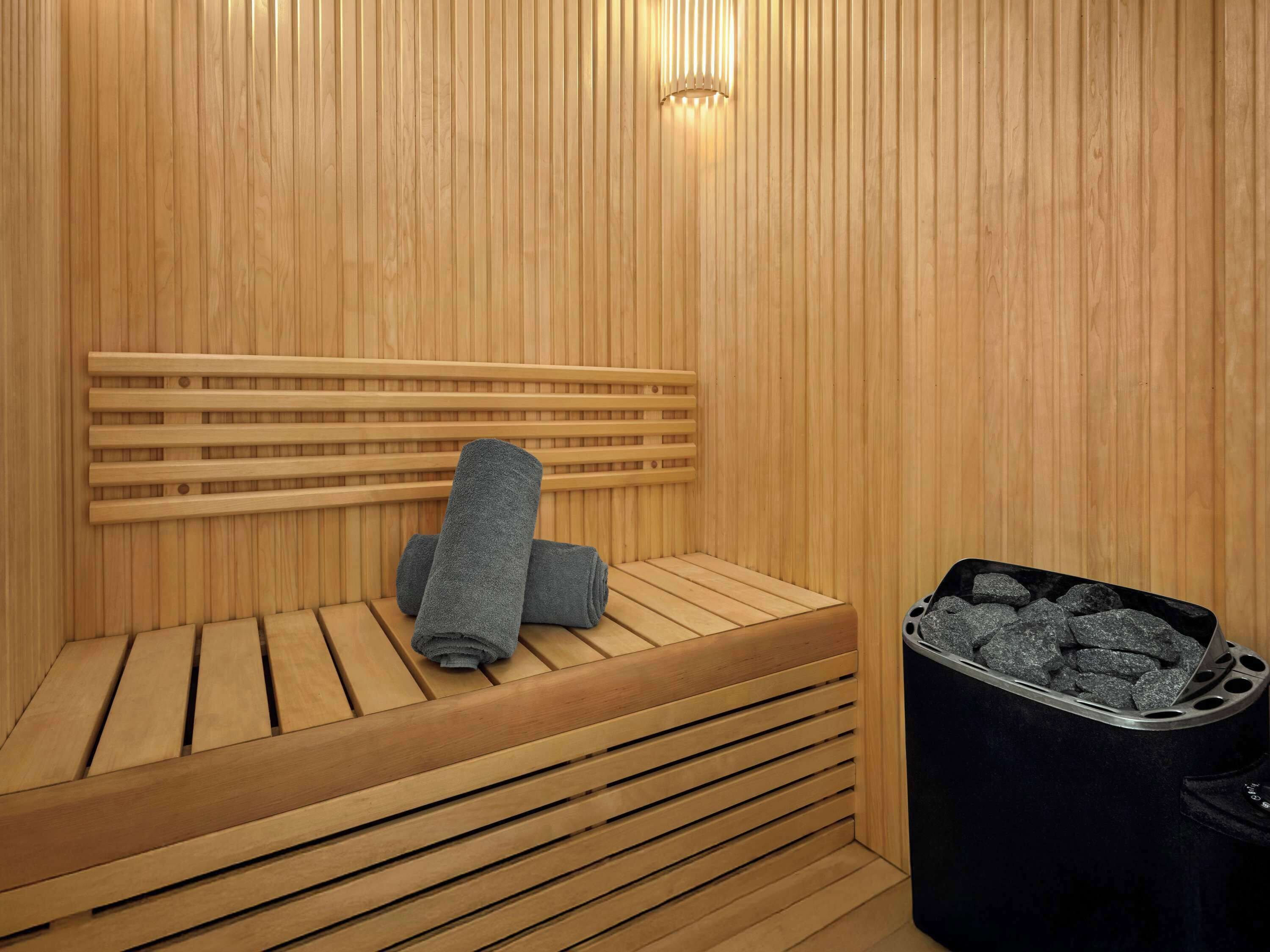 Una sauna de madera con un banco, una toalla y un recipiente para carbón.