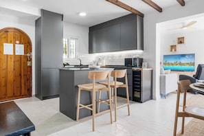 A modern kitchen with a central island, bar stools, and a dining area with a view of the ocean. - Panoramic terrace panthouse with sea view - Ref 129 (Mijas)