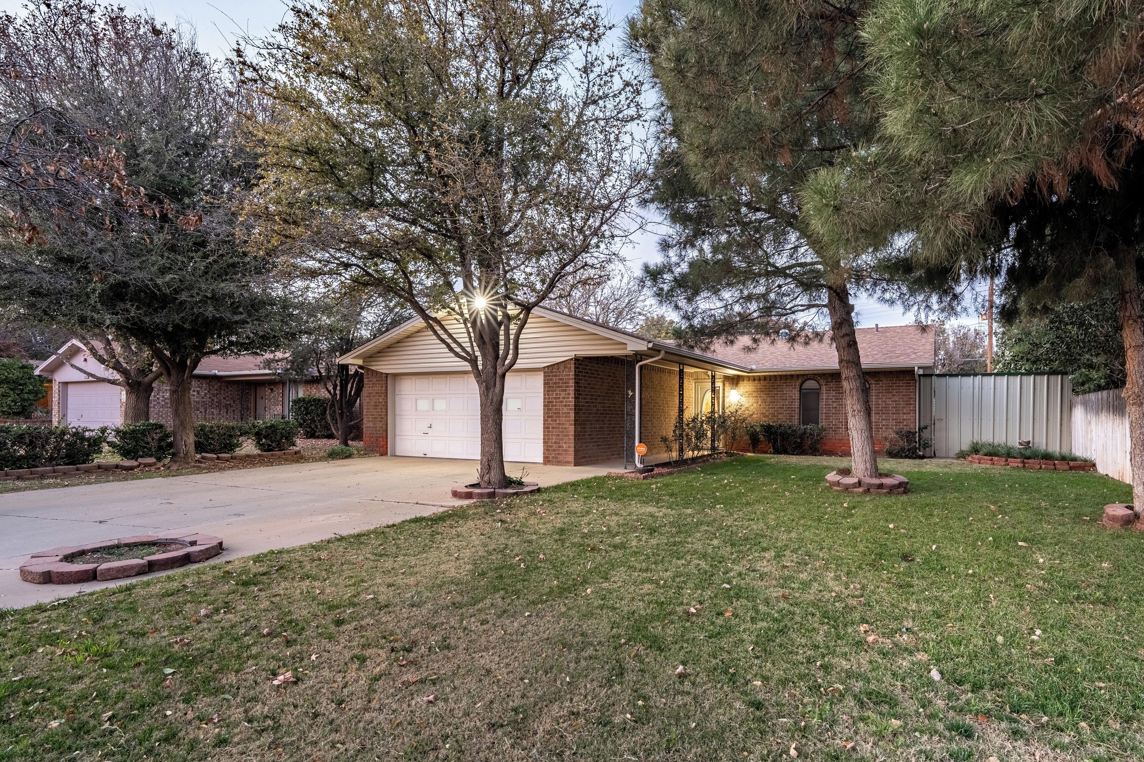 A residential house with a garage, a driveway, and a well-maintained lawn.