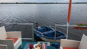 Un bote amarrado en aguas tranquilas, con una mesa dispuesta para comer y una fila de sillas de mimbre.