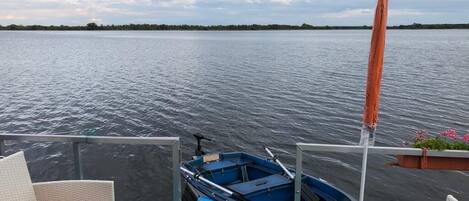 Een boot afgemeerd op een kalme waterpartij, met een gedekte tafel en een rij rieten stoelen.
