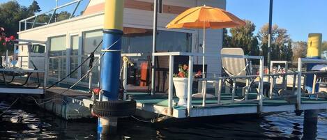 A floating house with a covered deck and an umbrella.