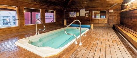 A wooden interior with a hot tub, wooden flooring, and windows.