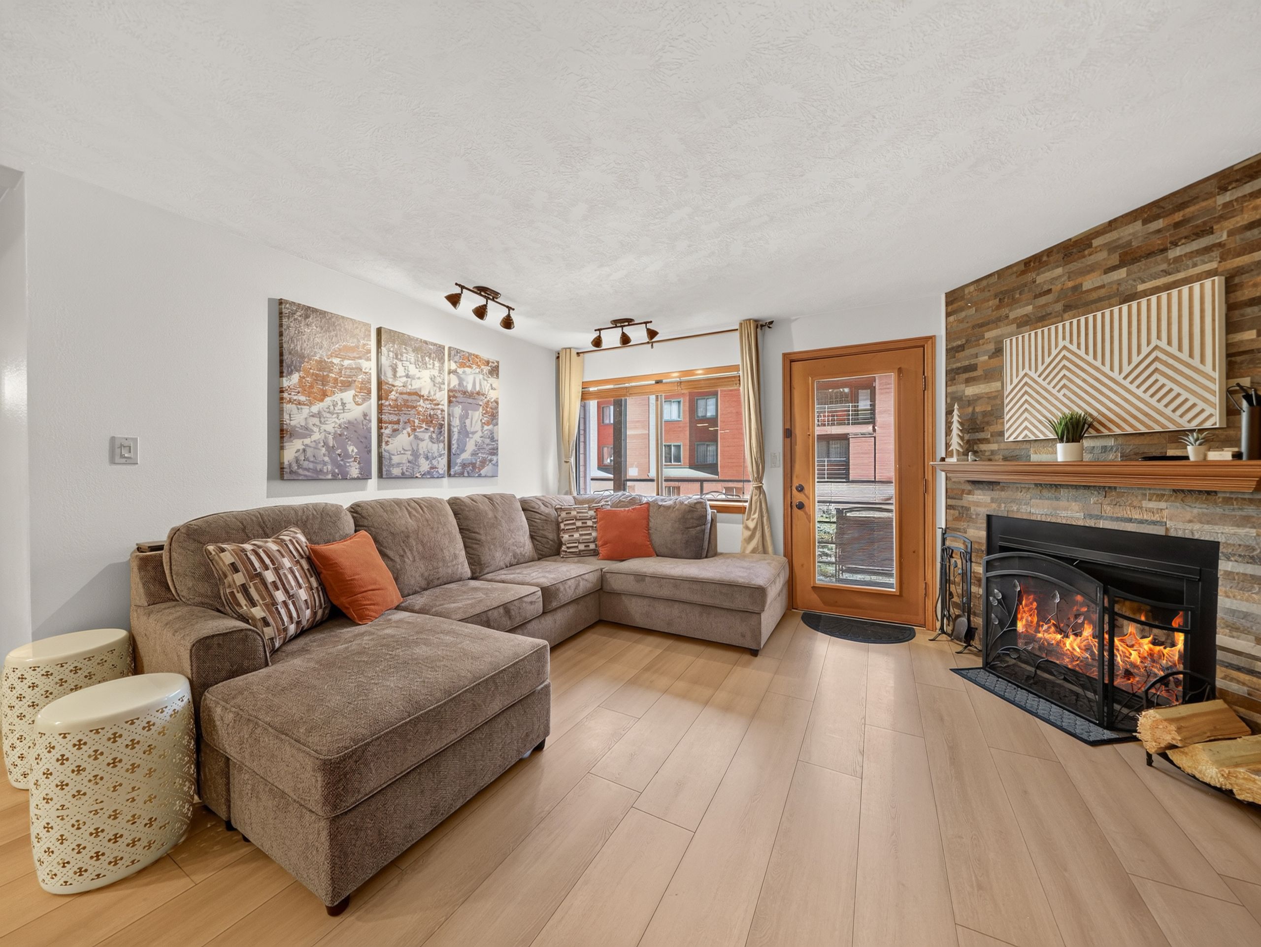 Sink into the plush sectional and feel the warmth of the crackling fireplace as you unwind in this inviting living space with stylish wood accents and soft natural light.