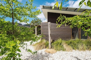 Un bâtiment moderne doté d’un toit en pente, entouré de verdure et bordé d’un chemin de gravier.