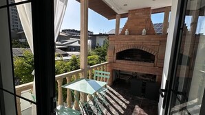 A balcony with a glass table and chairs, a brick fireplace, and a view of the cityscape. - Garden Lounge Hotel (Yerevan)