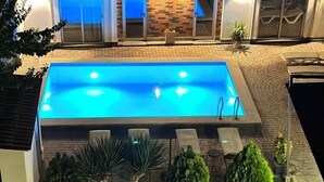 A rectangular swimming pool with a tiled deck, surrounded by a well-maintained lawn and potted plants. - Garden Lounge Hotel (Yerevan)