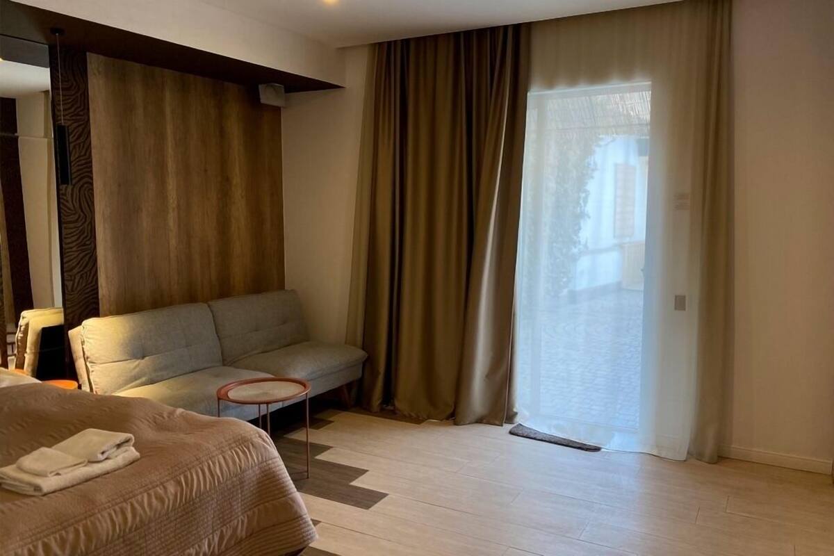 Una habitación de hotel con una cama, un sofá, una mesita y un ventanal corredero.