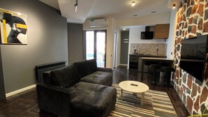A modern living room with a black sofa, a round coffee table, and a patterned rug. - Garden Lounge Hotel (Yerevan)
