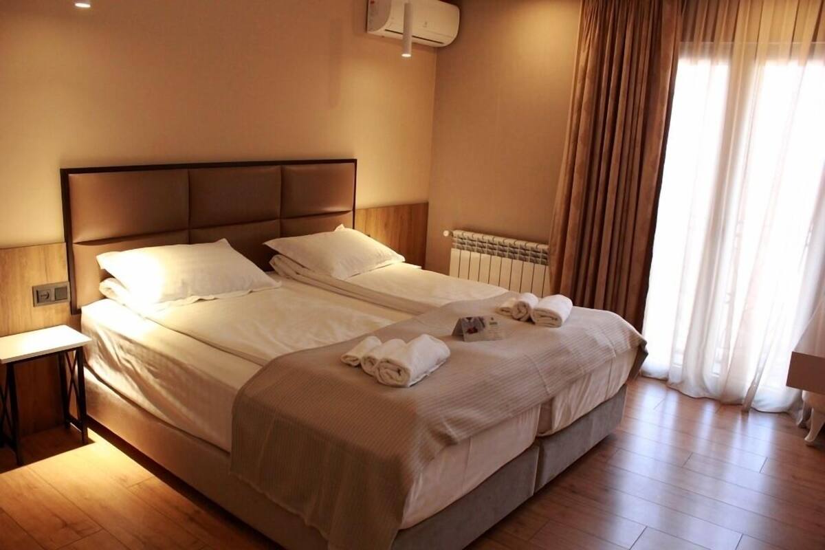 Una cama doble con cabecera, una mesita de noche y un radiador.