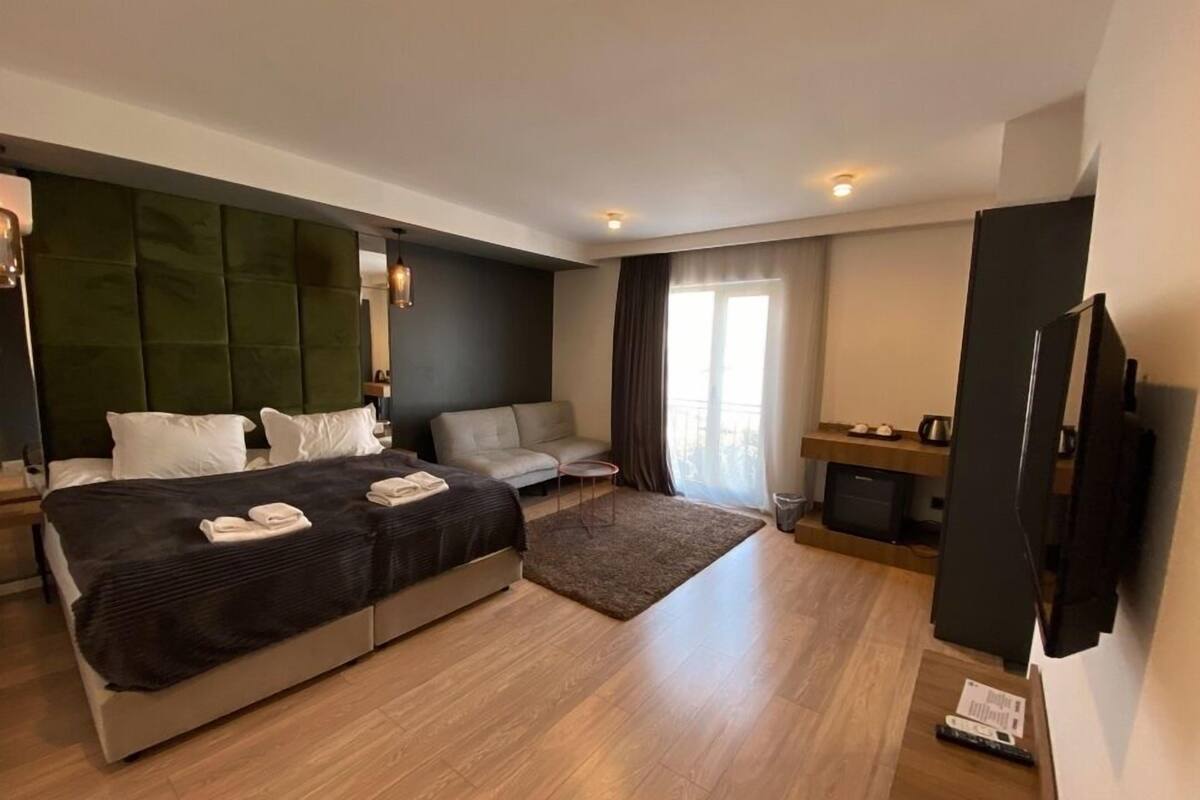 Una habitación de hotel moderna con una cama grande, un sofá, un televisor y una pequeña mesa.