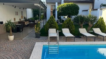 Relax by the pool surrounded by a paved walkway and lounge chairs.