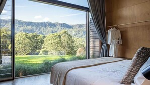 Ein Schlafzimmer mit großem Fenster, einem Bett und einem an der Wand hängenden Bademantel.