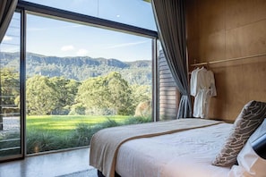 Una camera da letto con un'ampia finestra, un letto e un accappatoio appeso al muro.