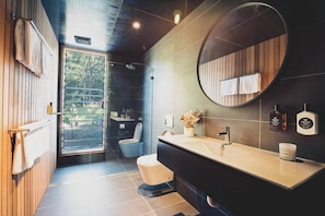 Un bagno moderno con un mobile bagno in legno, uno specchio rotondo e un water.