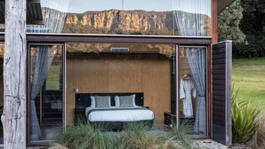 Ein modernes Schlafzimmer mit Bett, Vorhängen und Blick auf eine Berglandschaft.