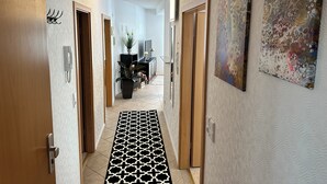 Un corridoio con pareti decorate da un motivo, un tappeto a contrasto bianco e nero e porte che danno su diverse stanze.