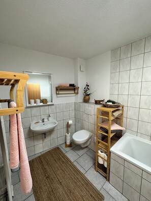 Ein modernes Badezimmer mit einem Holzwaschtisch, einem Waschbecken, einer Toilette und einer Badewanne.