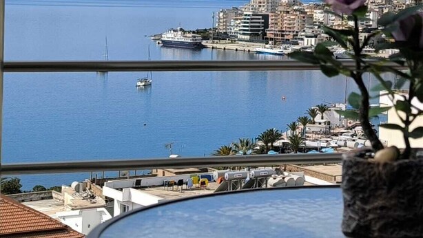Une vue d’une marina avec des bateaux, un paysage urbain et des montagnes en arrière-plan.