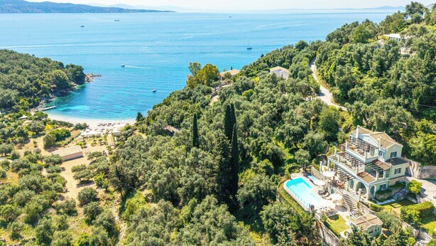 Une vaste villa dotée d’une piscine, entourée d’une végétation luxuriante et offrant une vue sur une étendue d’eau importante.
