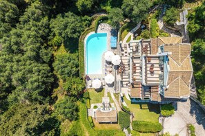 Eine Vogelperspektive auf ein Resort mit Schwimmbad, Sitzgelegenheiten im Freien und einem stufenförmigen Gebäude.