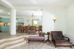 Een ruime woonkamer met een eettafel, stoelen, een bankje en een fauteuil.