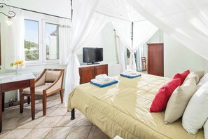 Een slaapkamer met een bed, een televisie, een bureau en een stoel.