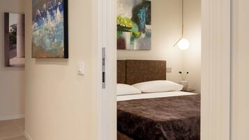 A modern bedroom with a large bed, a headboard, and two abstract paintings on the wall.