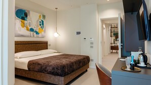 Una habitación de hotel moderna con una cama grande, un escritorio con televisor de pantalla plana y un cuadro en la pared.