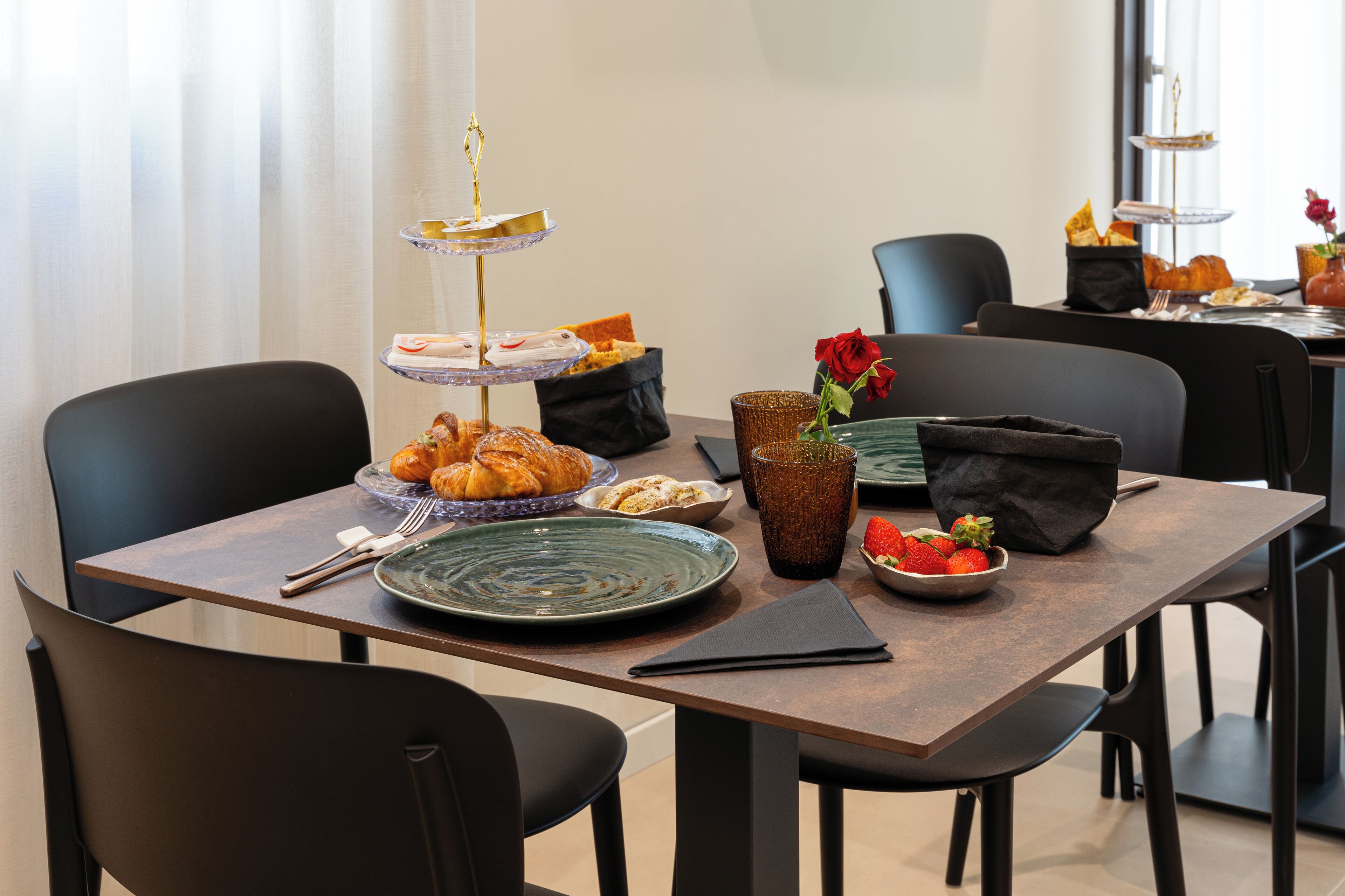 A dining table set with plates, bowls, a glass, and a vase with flowers.