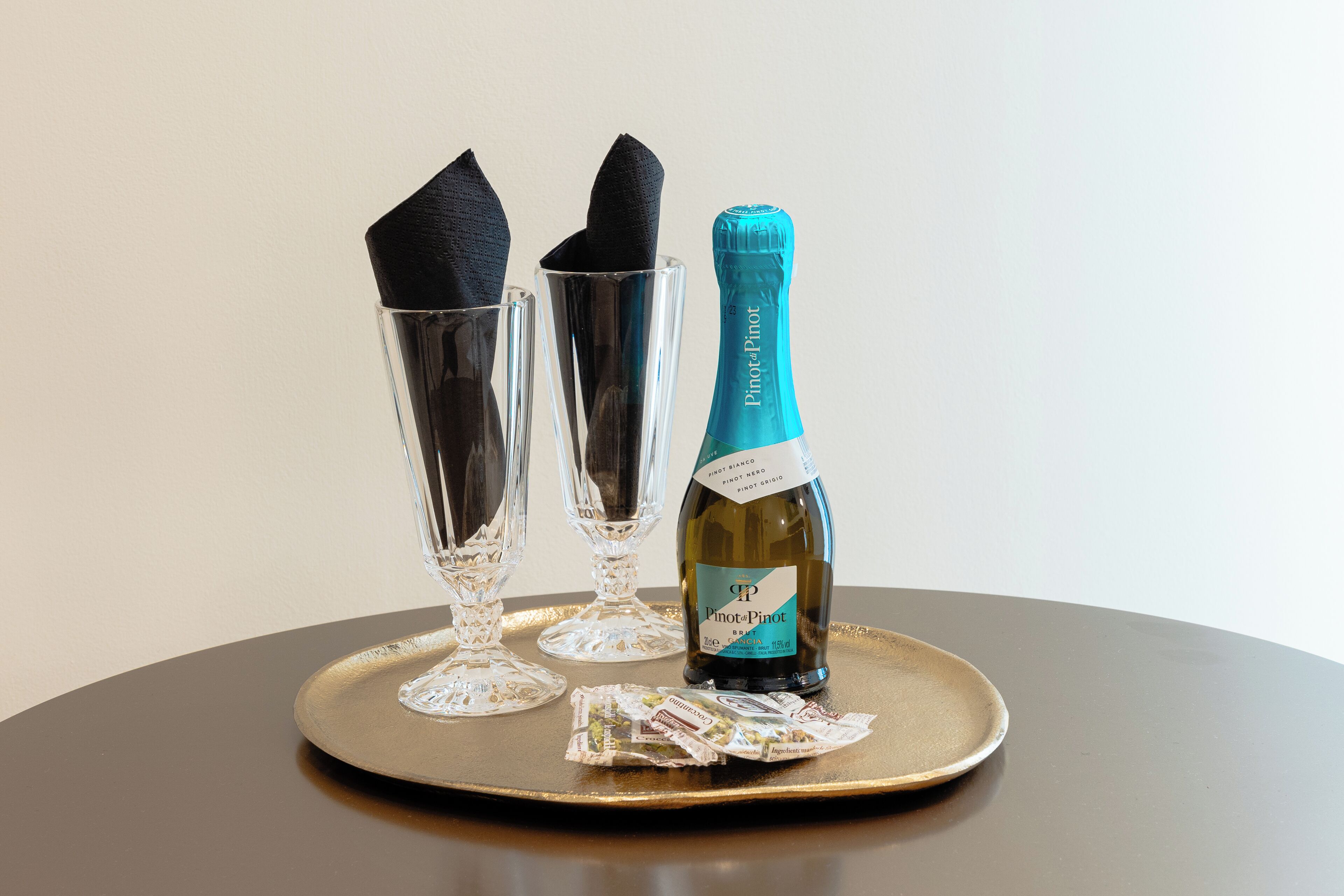 Een fles Pinotot op een dienblad met twee lege glazen en een servet.