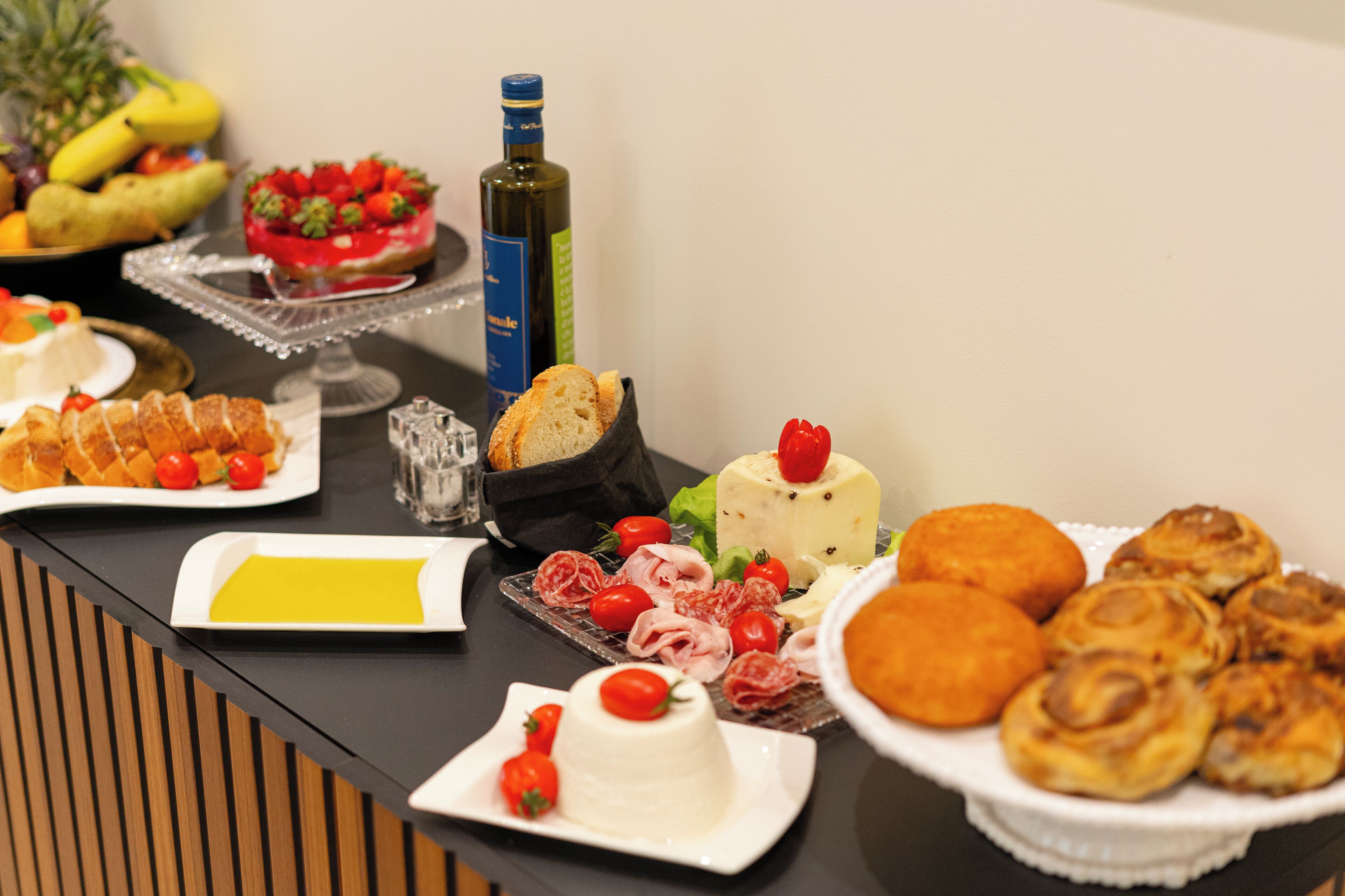Una mesa de buffet con diversos alimentos, incluyendo queso, pasteles y frutas.