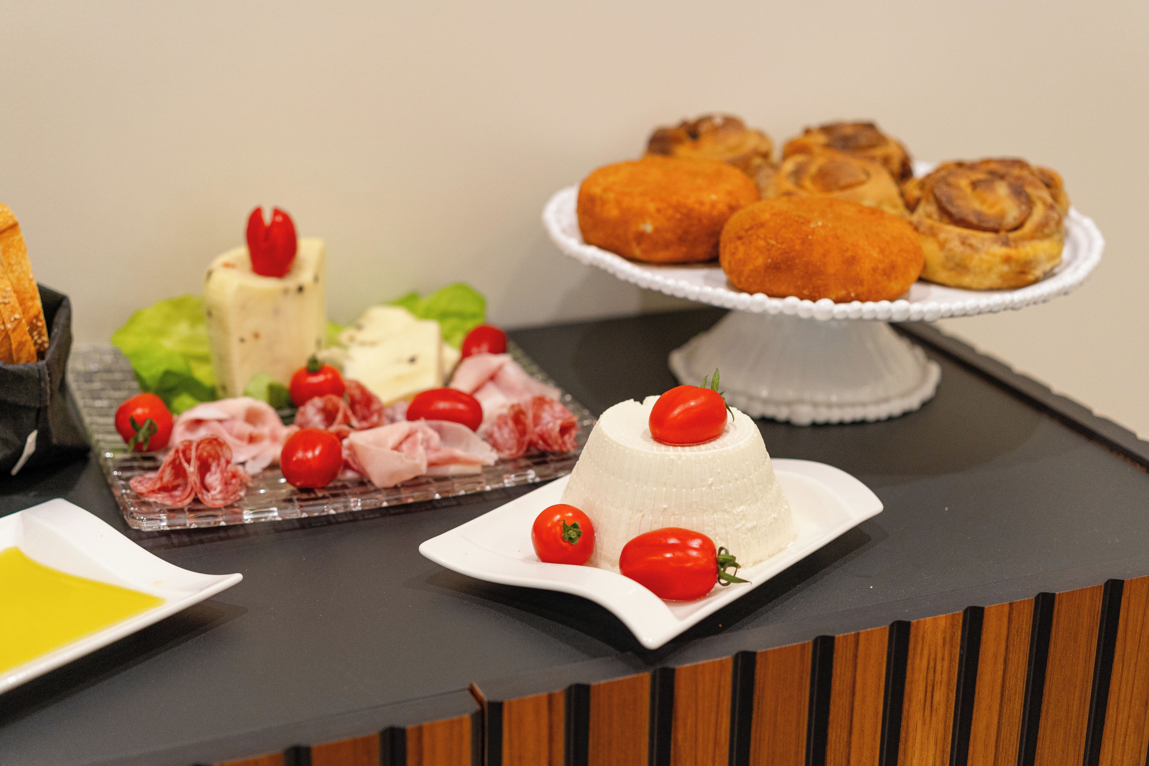 A buffet table with various food items including a white cheese dish, meat, and pastries.