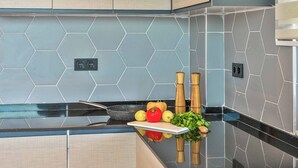 A kitchen with hexagonal tile backsplash, a black countertop, and wooden cabinets.