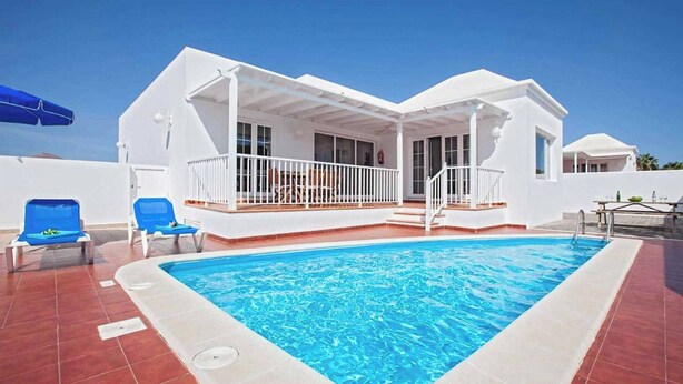 A swimming pool with a white house in the background. - Villa Dolores - Three Bedroom Villa, Sleeps 6 (Puerto del Carmen)