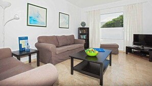 A living room with a sofa, coffee table, TV, bookshelf, and artwork on the walls. - Villa Dolores - Three Bedroom Villa, Sleeps 6 (Puerto del Carmen)