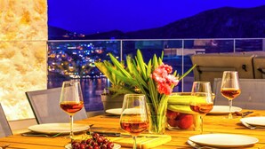 Une table à manger dressée avec des verres à vin, des assiettes et un vase rempli de fleurs.