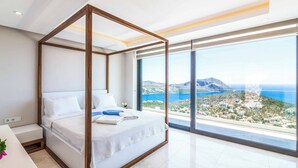 Un lit à baldaquin avec vue sur la mer et un paysage montagneux.