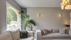 A modern living room with two sofas, a coffee table, and a large window providing a view of greenery outside.