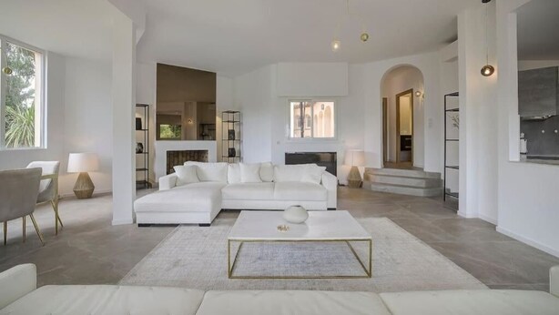 A spacious living room with a large white sectional sofa, a coffee table, and a fireplace.