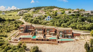 Una zona residencial en una ladera con varias casas, una piscina y un jardín bien cuidado.