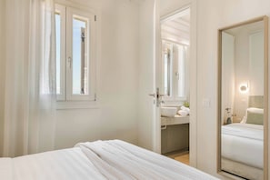 Hotellihuone, jossa on sänky, kylpyhuone, jossa on pesuallas ja peili, sekä ikkuna, jossa on verhot.