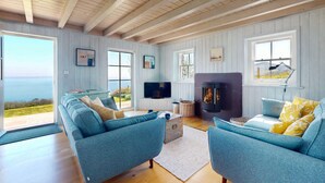 A spacious living room with a large sofa set, a television, and a fireplace. - Talarfor - Two Bedroom Cottage, Sleeps 4 (Rhiw)