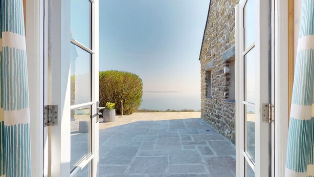 A stone building with a paved patio leading to a glass door. - Talarfor - Two Bedroom Cottage, Sleeps 4 (Rhiw)