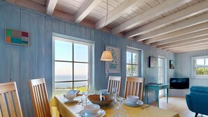 A dining area with a table set for four, wooden chairs, a television, and a view through the window. - Talarfor - Two Bedroom Cottage, Sleeps 4 (Rhiw)