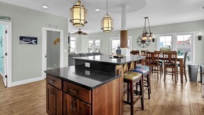 A kitchen with a central island, wooden cabinets, and pendant lighting. - Luxurious Escape Steps from the Beach w/ Pool, Dock, & Stunning Views (North Topsail Beach)