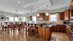 A spacious kitchen with wooden cabinets, a large island, and pendant lighting. - Luxurious Escape Steps from the Beach w/ Pool, Dock, & Stunning Views (North Topsail Beach)