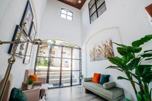 A spacious room with a large sliding glass door leading to an outdoor area, a sofa with colorful cushions, and a large potted plant.
