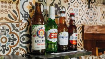 Une étagère avec quatre bouteilles de bière, le tout placé devant un mur à motifs.
