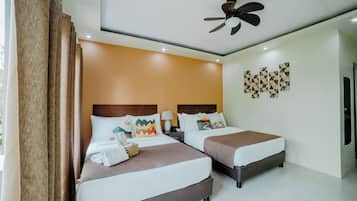 Ein Hotelzimmer mit zwei Betten, einem Deckenventilator und einer Wand mit geometrischer Wandkunst.